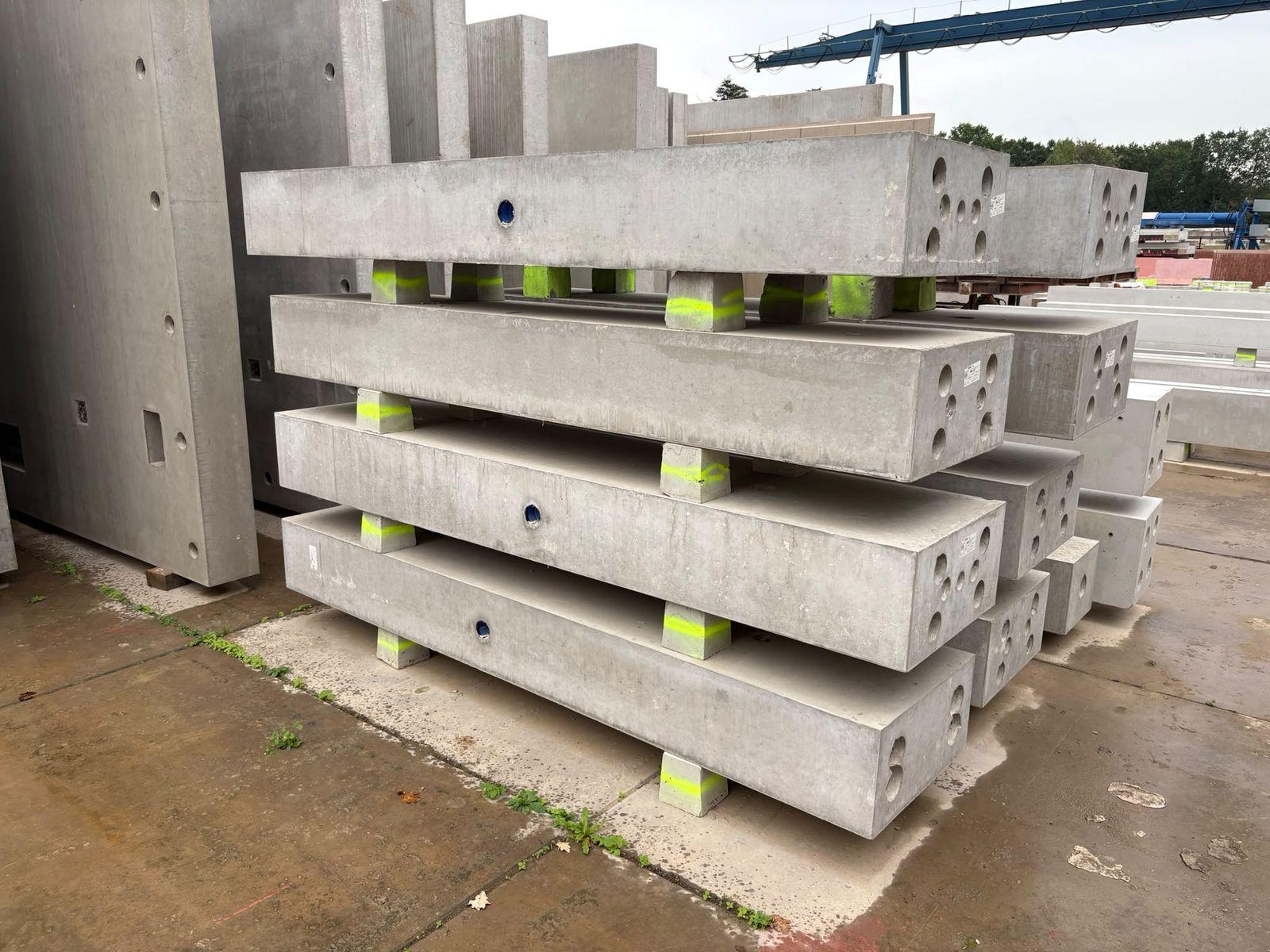 Gestapelde prefab betonnen liggers en kolommen op het fabrieksterrein